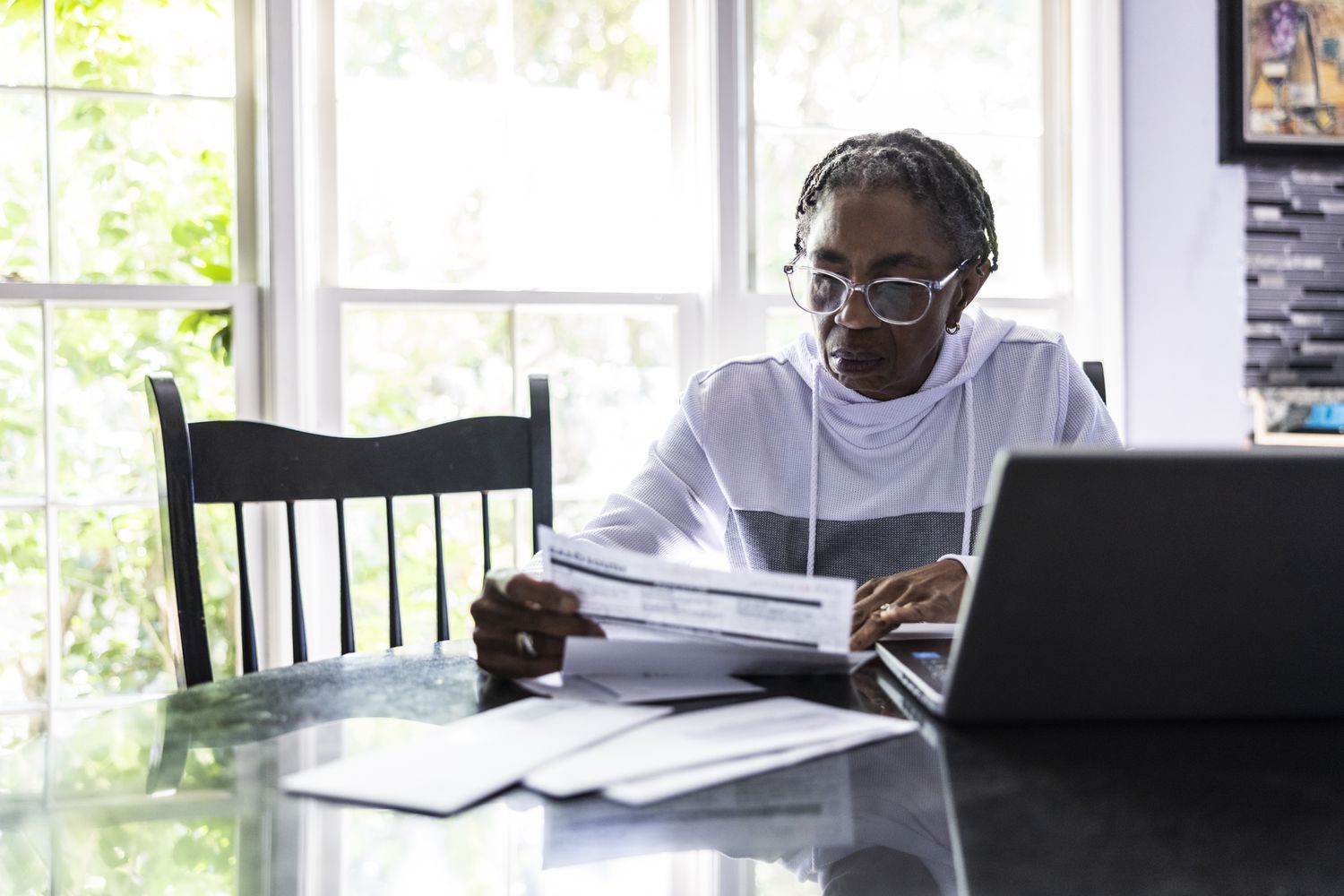 Woman paying bills or taxes using her laptop at her kitchen table