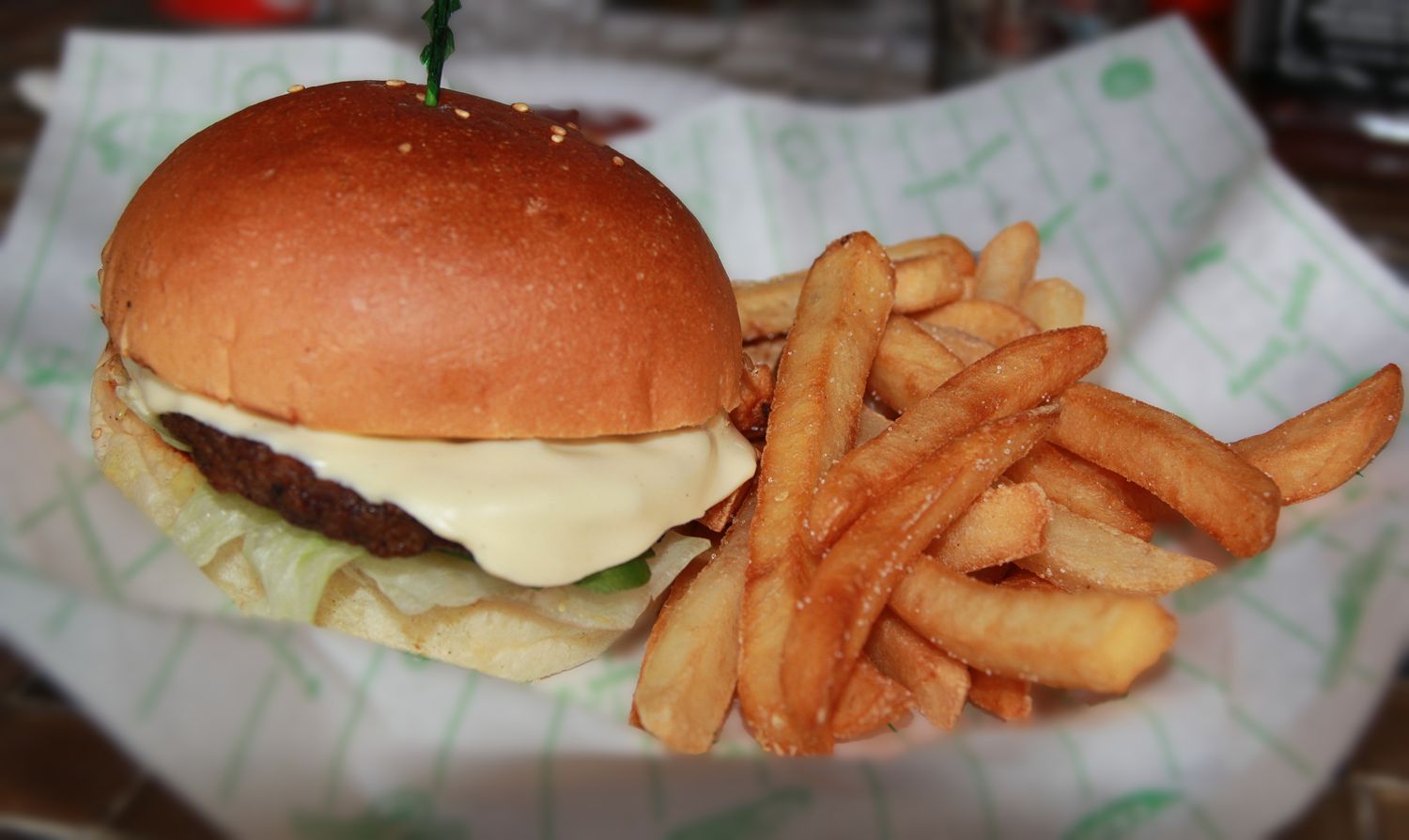 A cheeseburger and fries on a paper wrapper. 