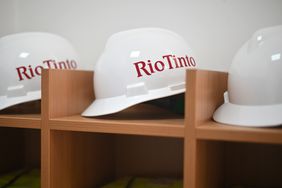 Three hardhats with the Rio Tinto logo written on the side sit on a shelf.