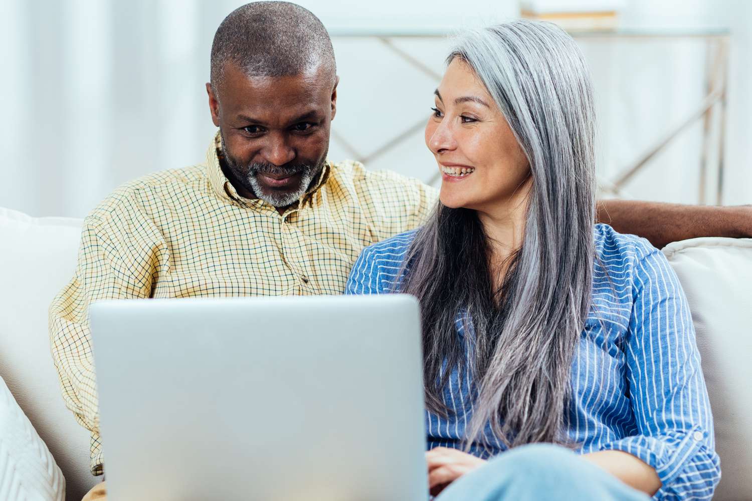Couple smiling on couch with a laptop
