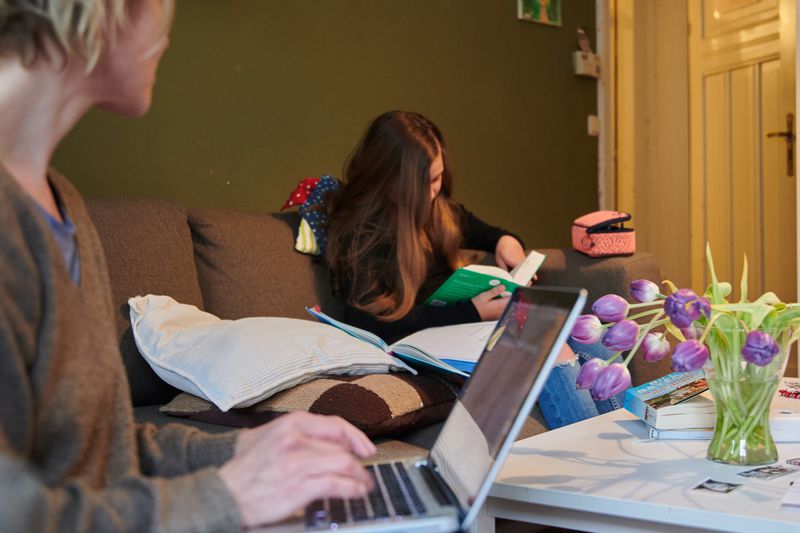 Man trading on his laptop. Woman in the background.