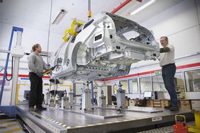 Two factory workers manufacturing a car