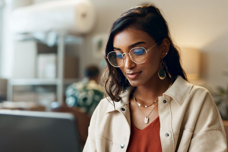 Woman looking at a laptop screen in an office setting. 