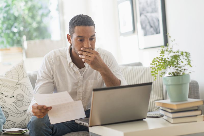 A man reviews documents and uses a laptop.