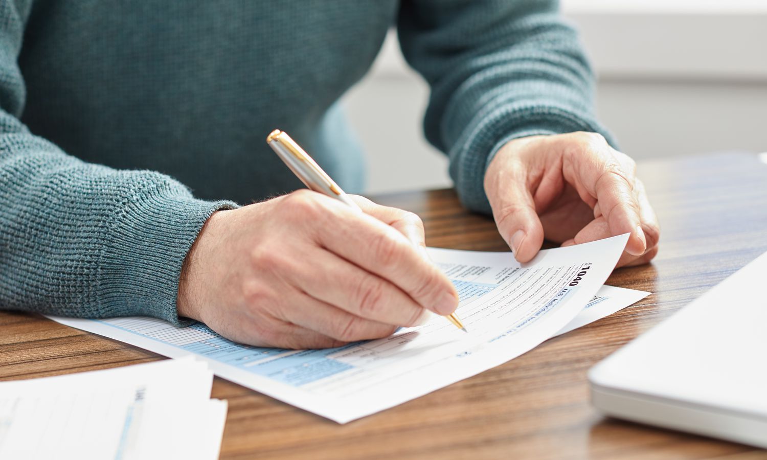 Person holding a pen and filling out a tax form