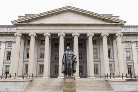 A view of the outside of the U.S. Treasury Department, with a statue in front.