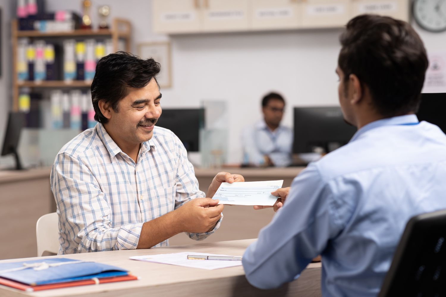 Middle aged man receiving a check from a bank employee