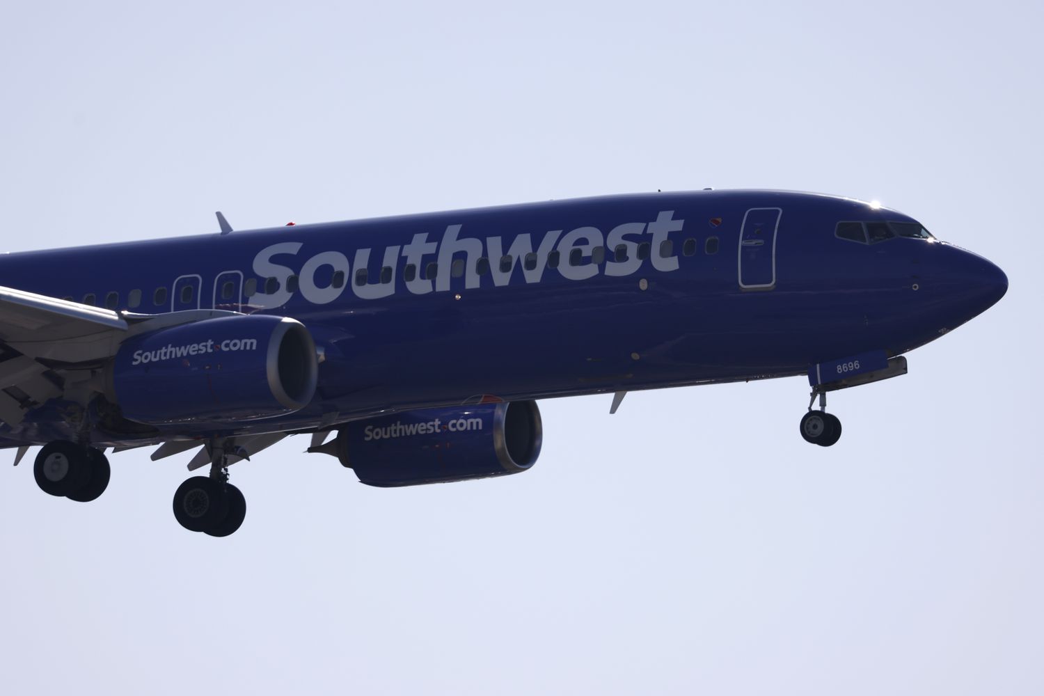 A blue Southwest Airlines plane in the sky with its landing gear extended