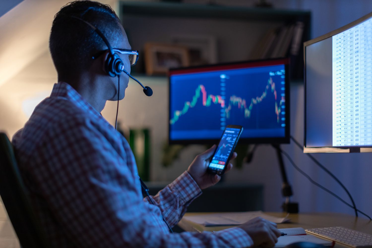 A person looks at a currency trading app on their smart phone from an office.