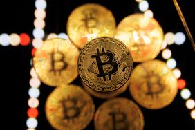 An illustration of golden physical bitcoins on a multicolored background. 
