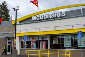 A person walks into a McDonald's restaurant, with the company's logo on the side of the building