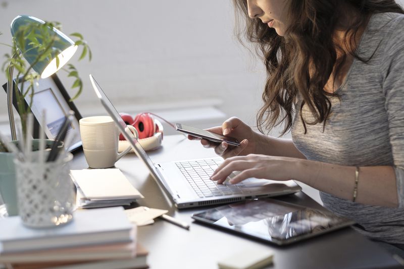 woman researching on computer and phone