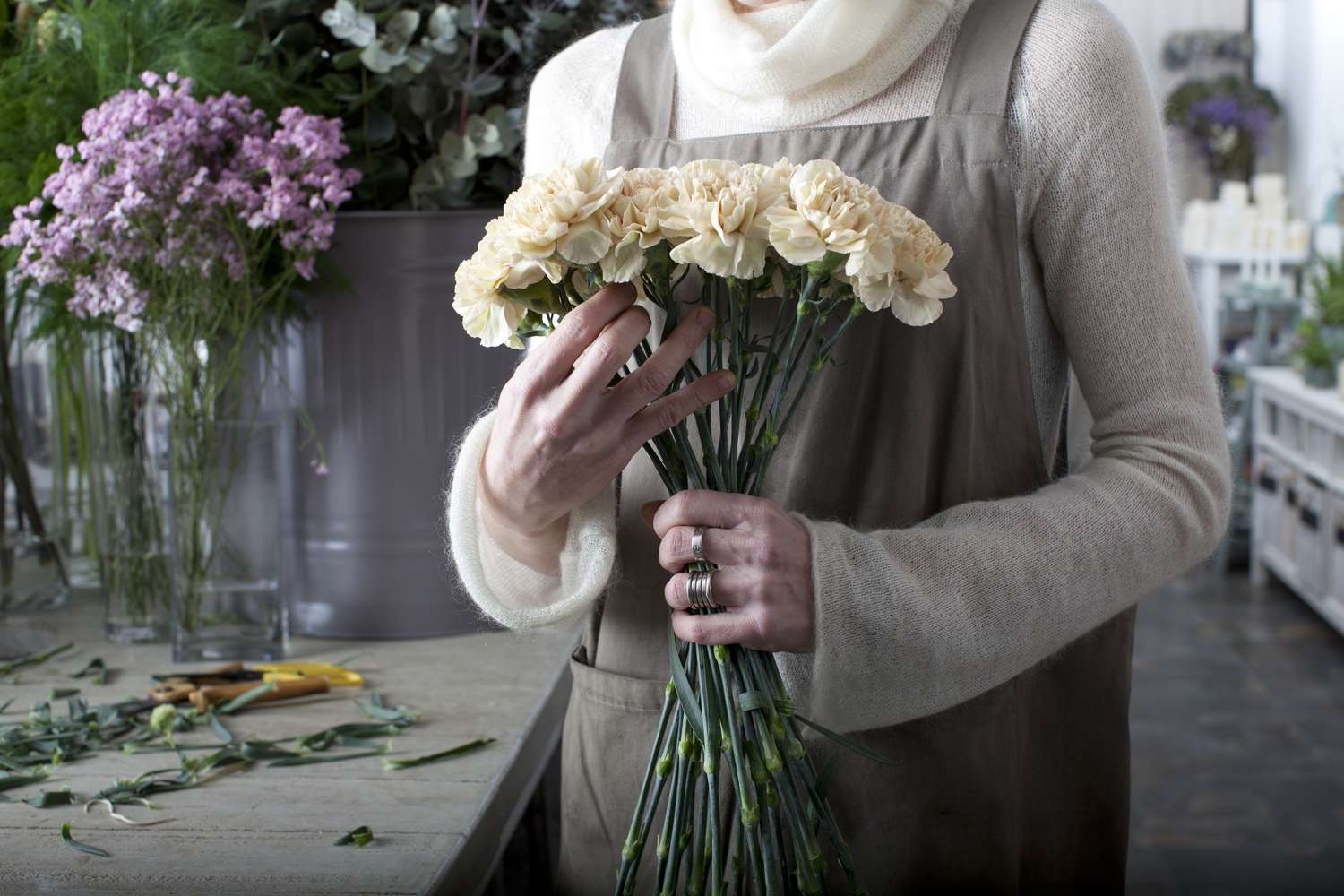 Close-up of a person working in a floral shop holding an arrangement of flowers in their hands