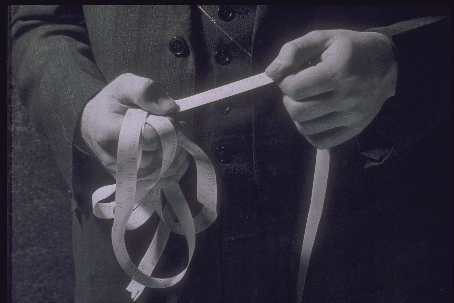 A vintage image of a business person reading an old-fashioned ticker stock tape.