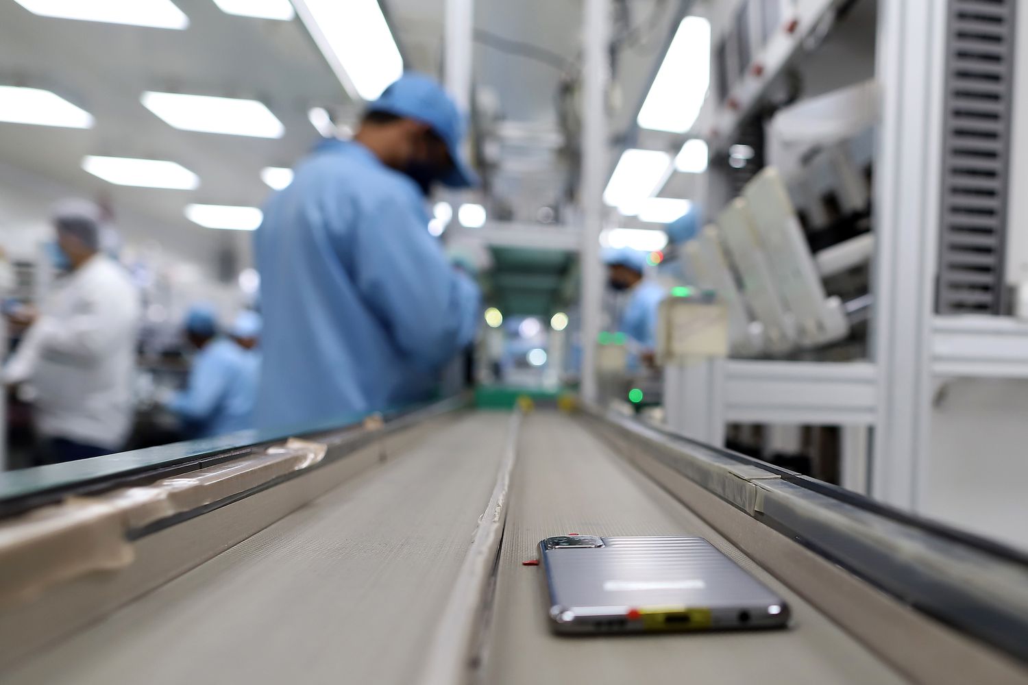 A smartphone moves along a conveyor on an assembly line at a Dixon Technologies factory in Noida, Uttar Pradesh, India