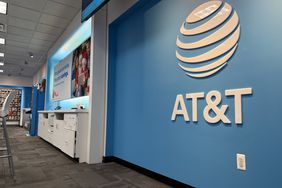 The AT&T logo is seen on a blue wall in an AT&T retail store.