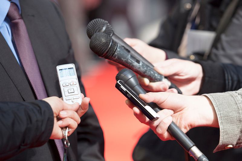 Midsection Of Reporters Holding Microphone By Businessman