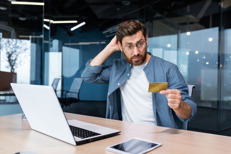 Man sitting in his office worrying about his credit card balance being reduced.