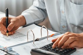 Corporate auditor calculating budget with calculator on his office desk
