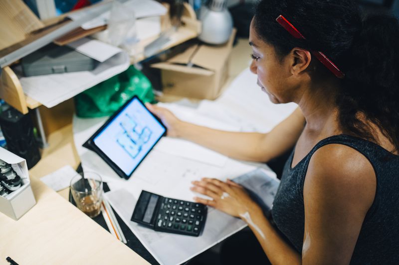 Small business owner using tablet while calculating finances