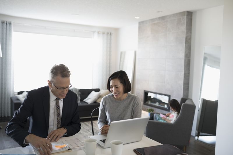 Financial advisor and woman with laptop meeting in dining room