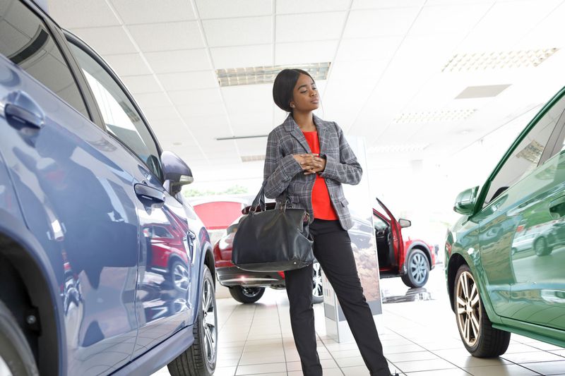 Young woman looking at cars in a showroom.