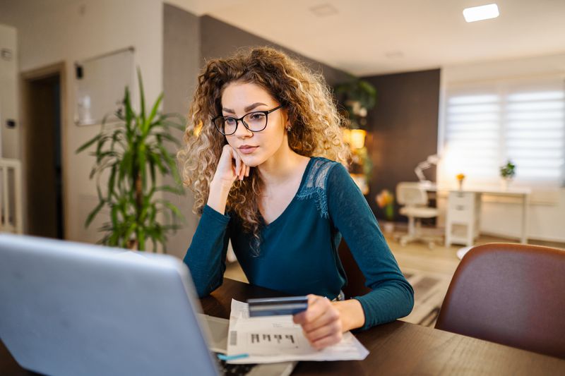 Young woman sitting at home considering credit card arbitrage opportunities
