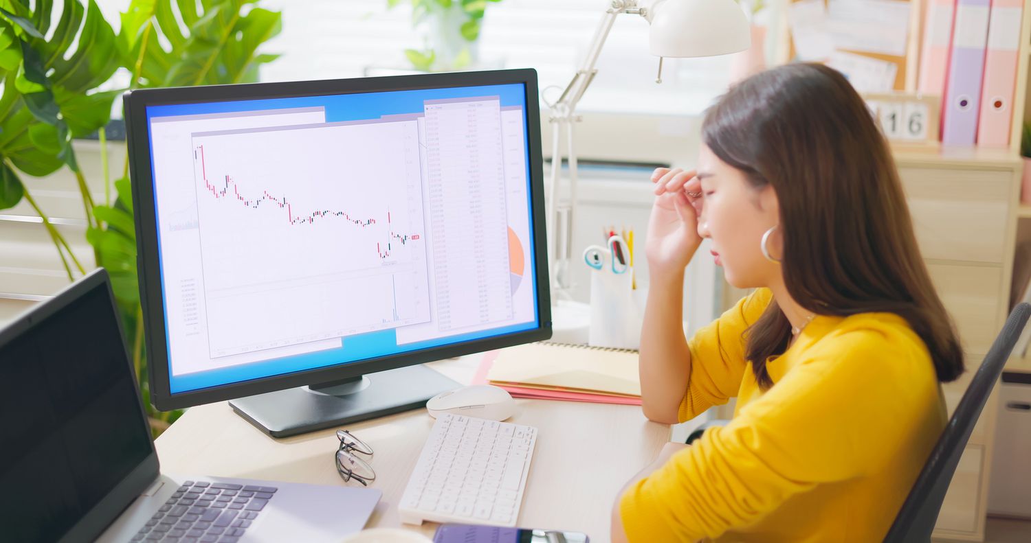 Woman looking at a chart showing a downtrend, displayed on her computer.