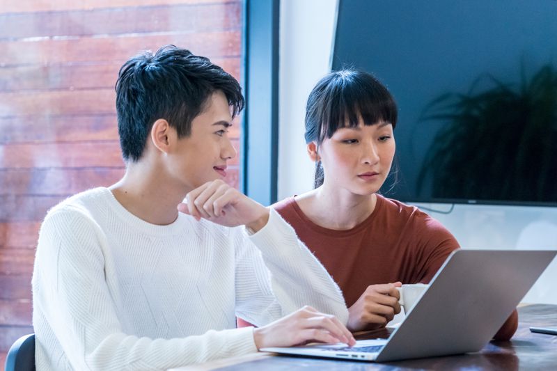 Young couple sitting at home and looking together at mortgage refinance rates on a laptop