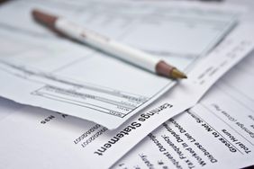 Pencil on pile of pay statements