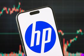 The logo of HP Inc. is displayed on a smartphone screen, with the latest stock market chart of the company in the background