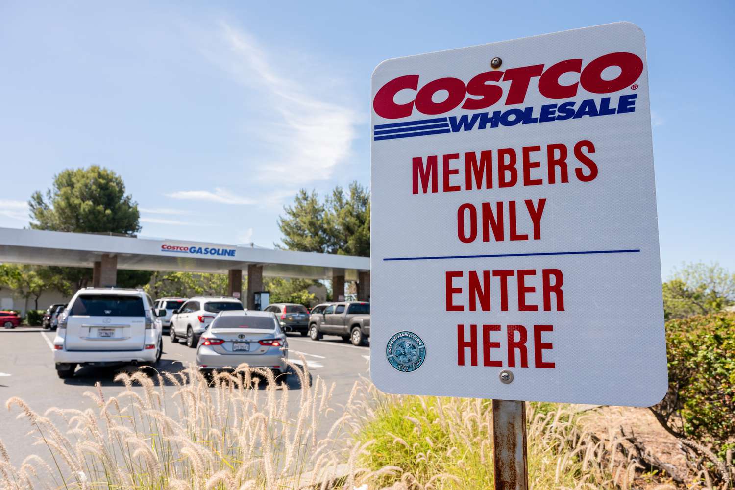 A white sign that says Costco Wholesale Members Only Enter Here is seen in front of a Costco gas station.