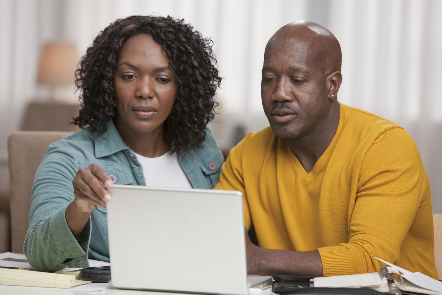 Couple in their 40s sitting at home and looking together at mortgage rates on a tablet