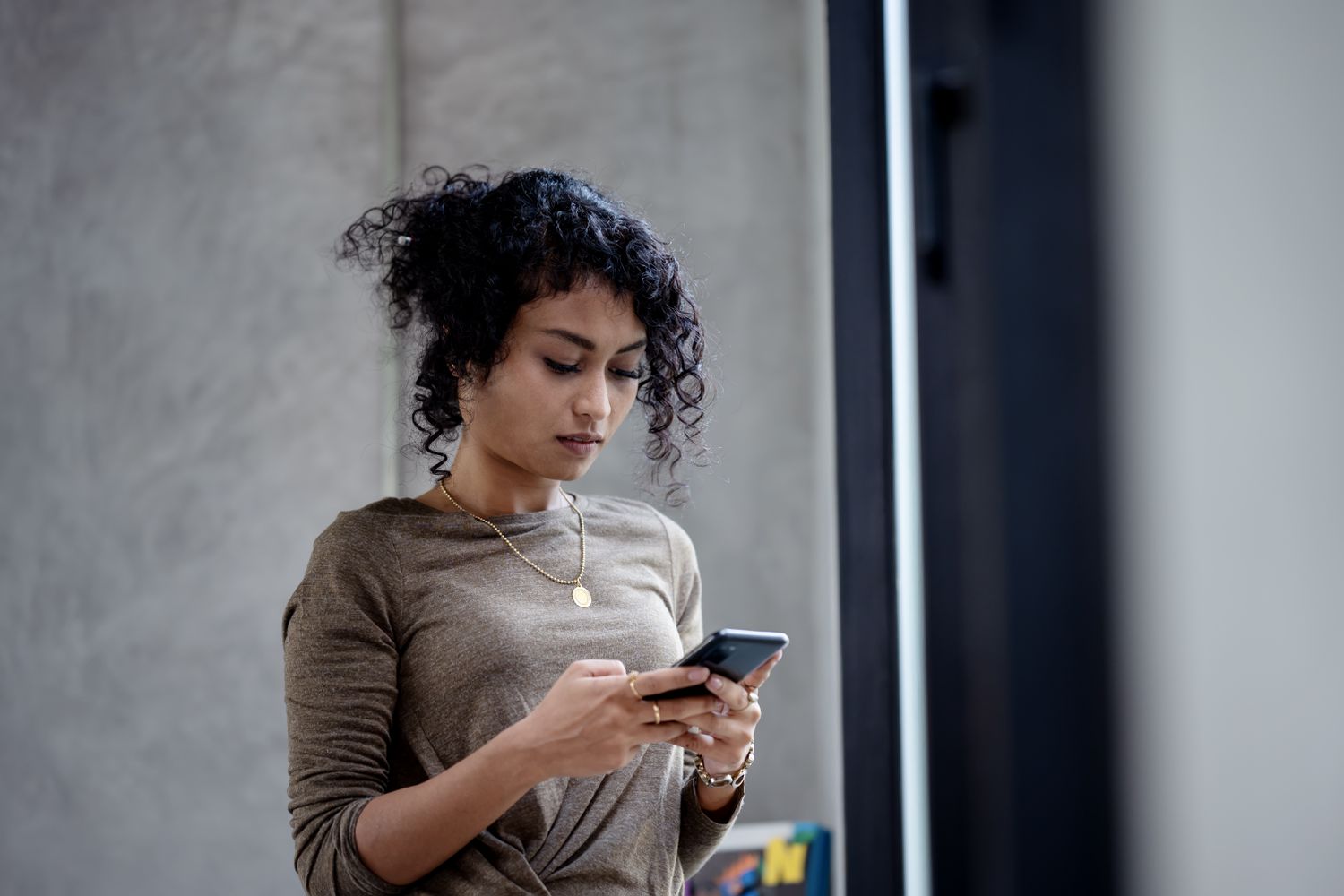 Young woman standing and looking intently at something on her smartphone