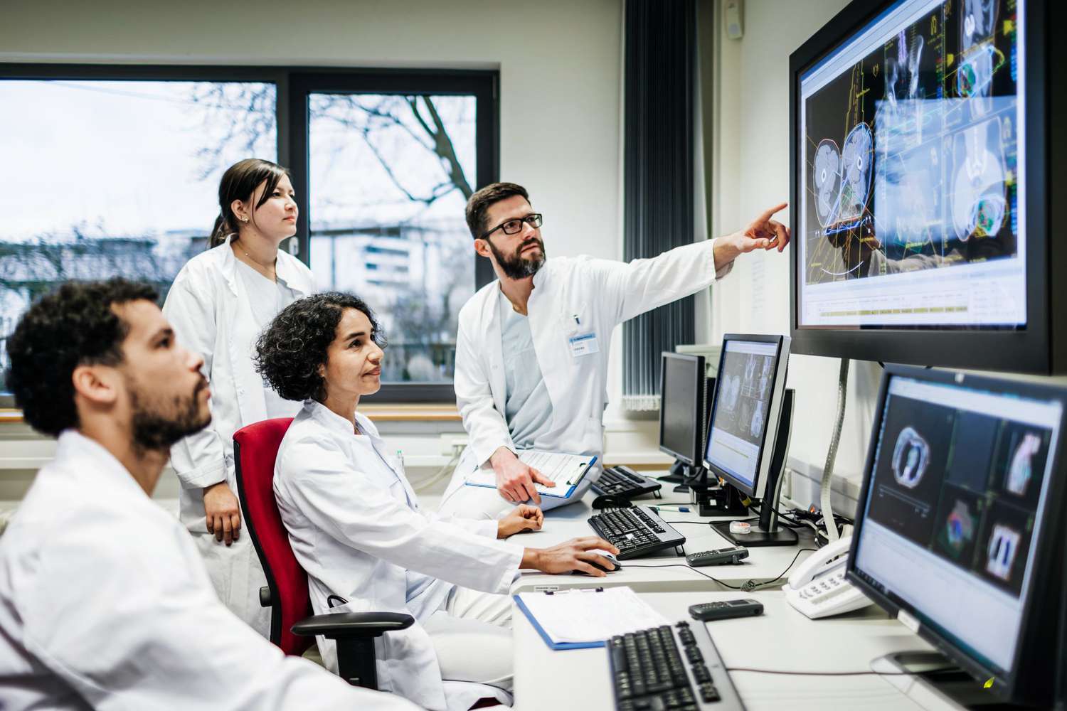 A team of doctors looks at lab results together on monitors
