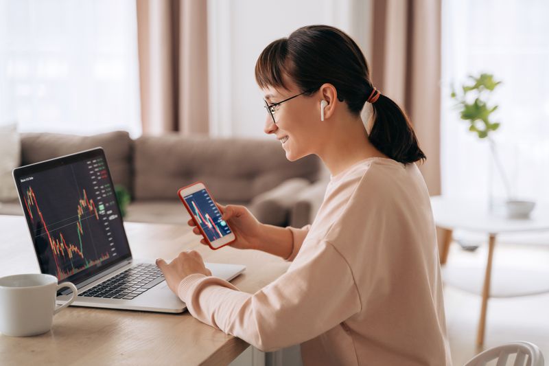 Trader looking at charts on laptop and mobile device