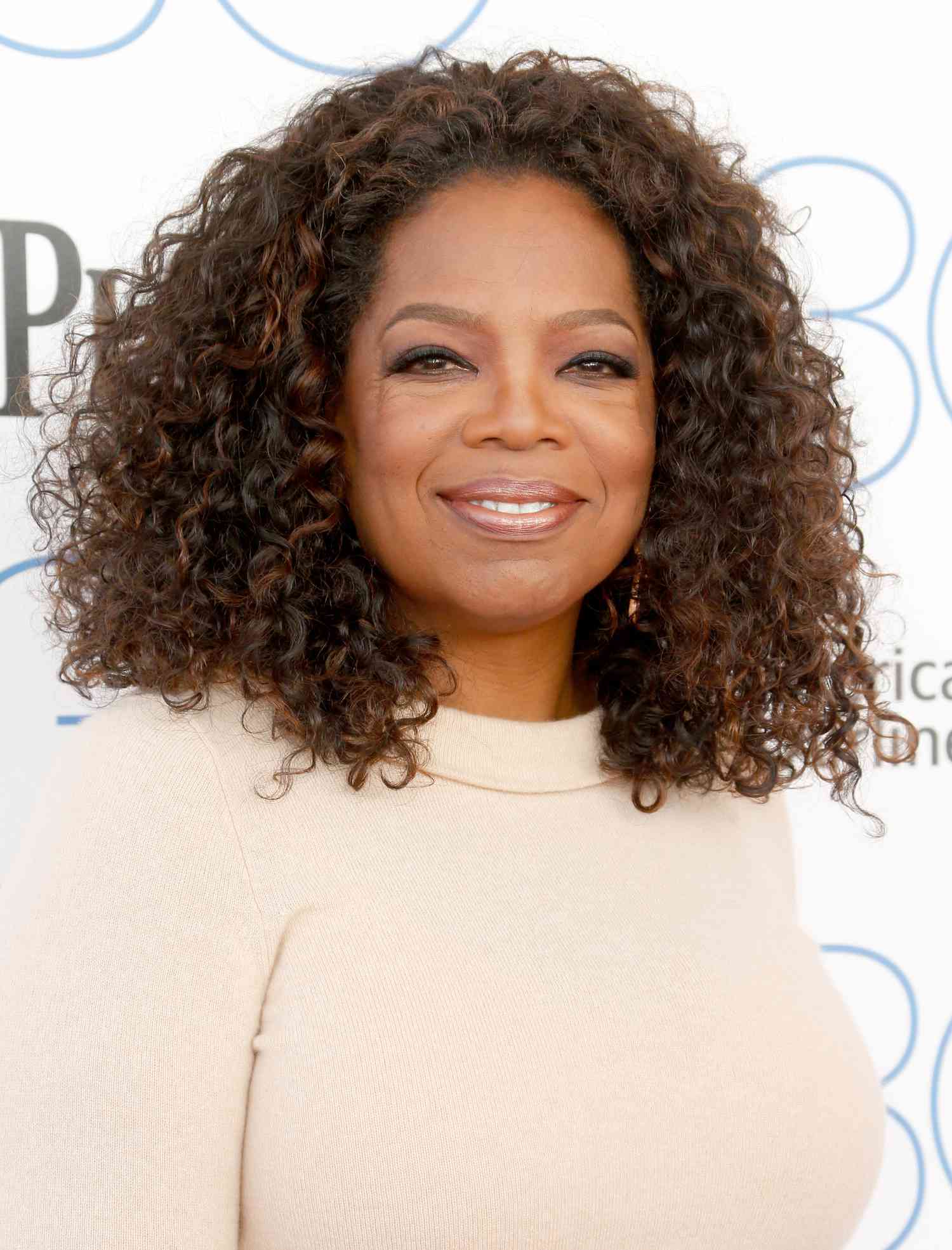 Oprah on red carpet in beige shirt