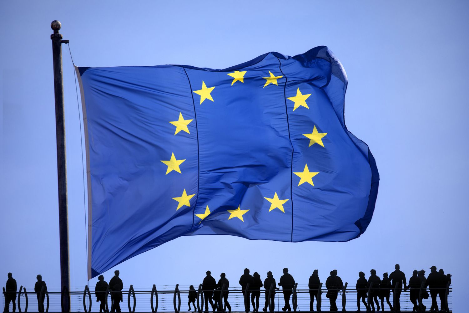 A group of people standing under the European Union flag