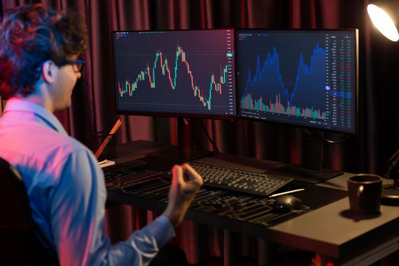 Trader looking at charts on two monitors