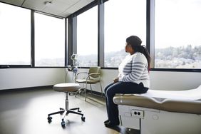 Side view of female patient sitting on bed at a doctor's office