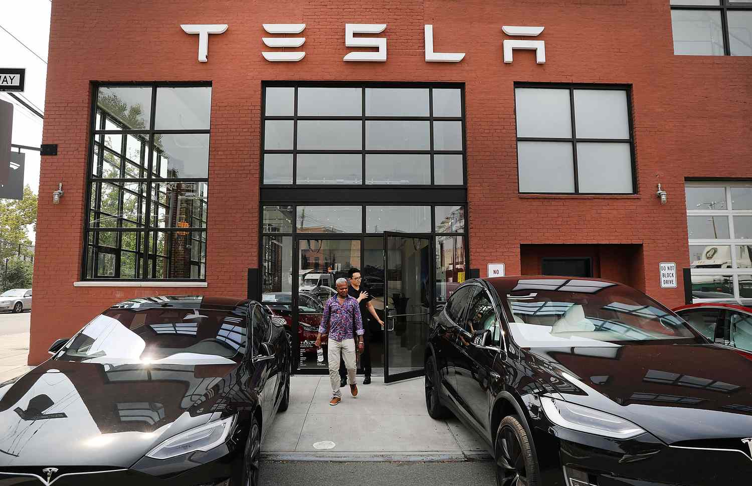 Two men stepping out of a Tesla showroom