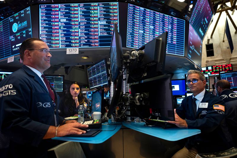 Two traders face computer screens while working at desks at the New York Stock Exchange.