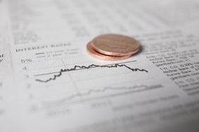 Stacked coins placed on a financial chart with line graphs