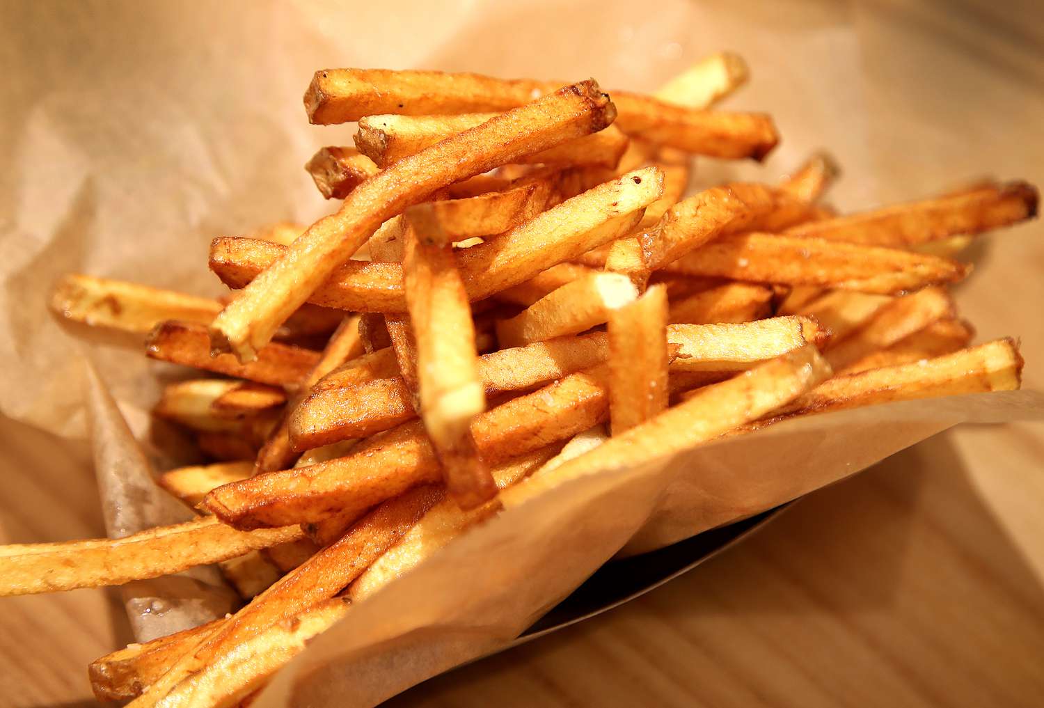 A container of French fries on a table. 