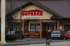 A person walks near an Outback Steakhouse restaurant. 