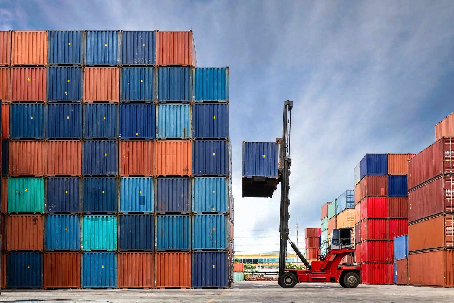 Crane lifting up container in yard full of containers. 