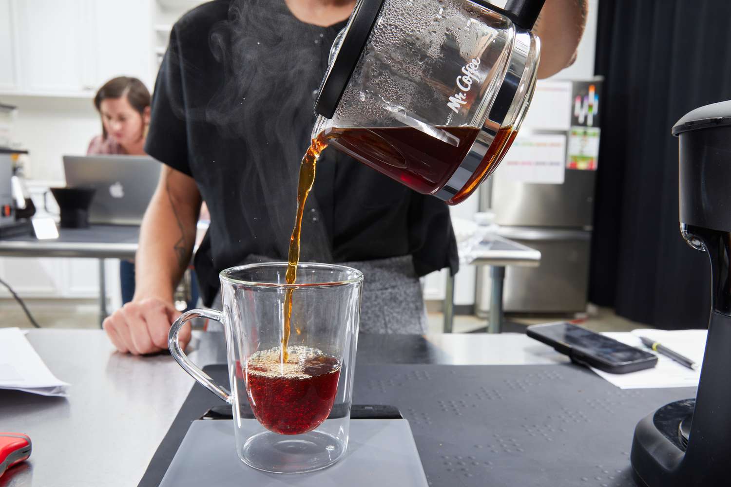 A person pouring a cup of coffee from the Mr. Coffee 5-Cup Mini Brew Coffee Maker