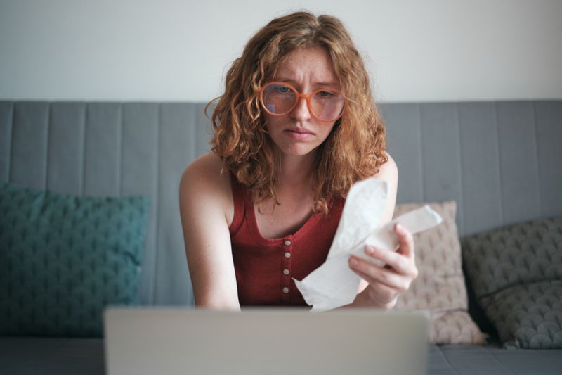 Student Holding Bills Looking Confused