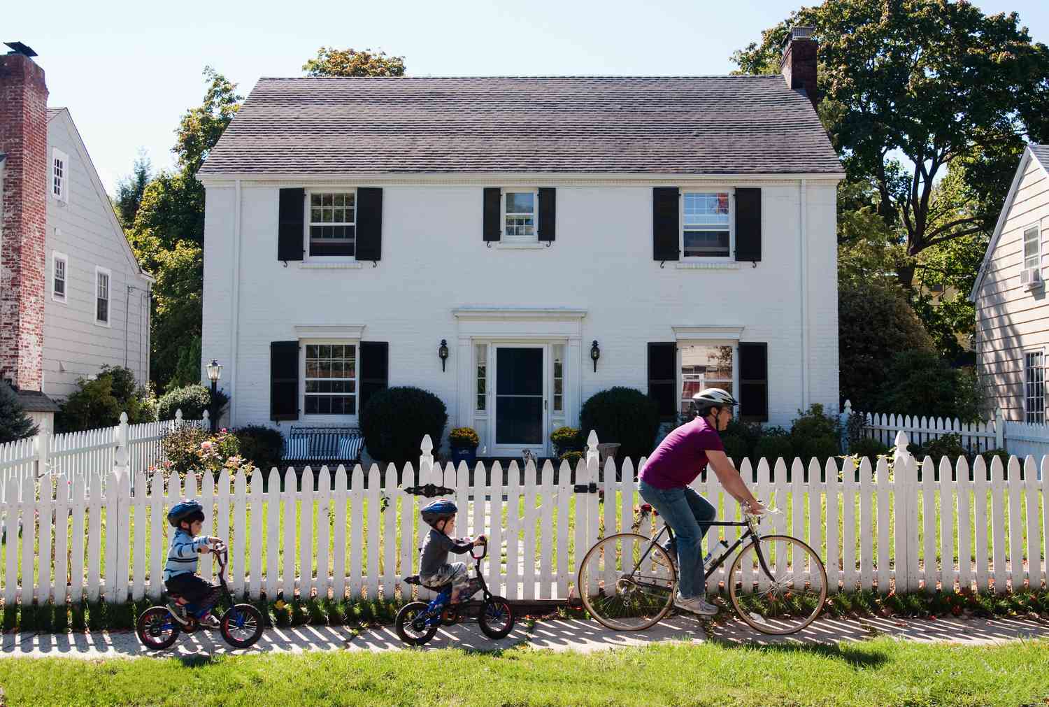 A family bikes in front of a home.