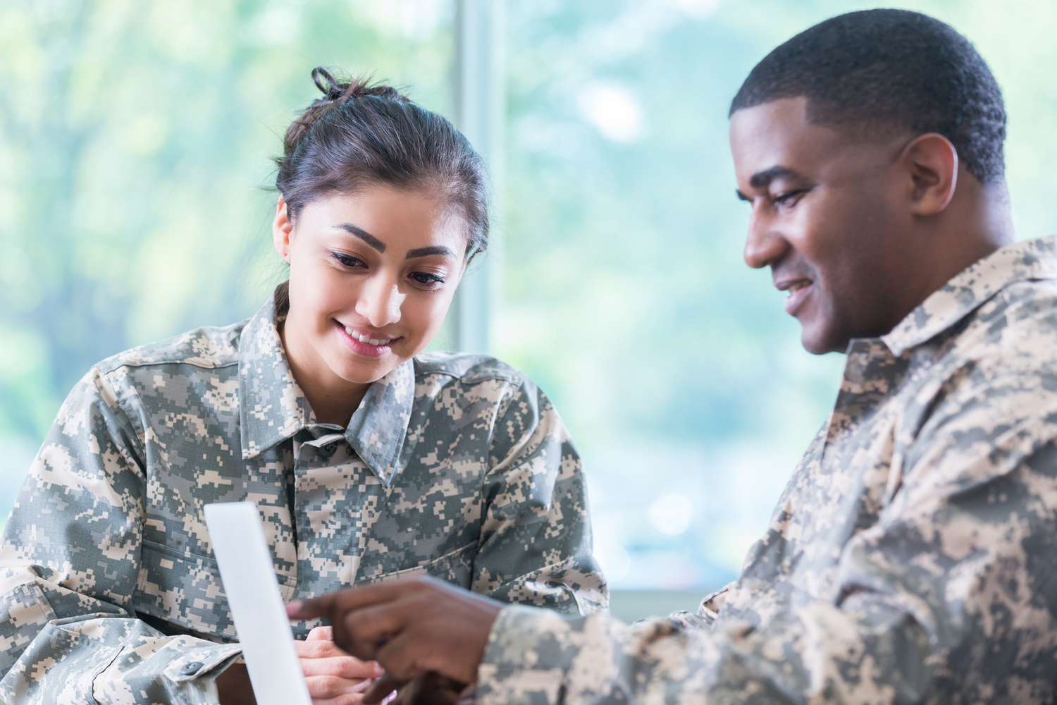 Two veterans discuss information on a laptop.